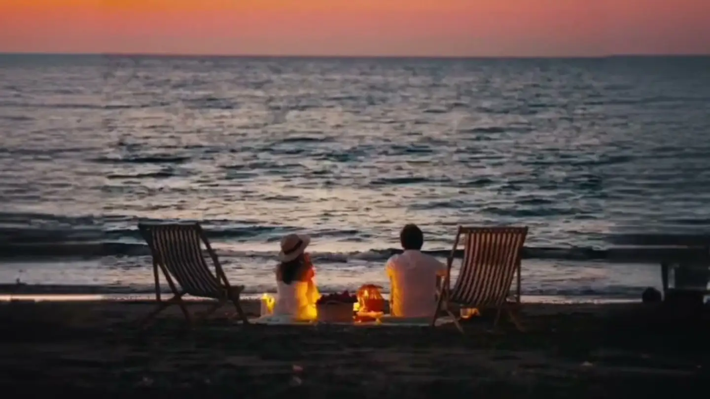 A couple having a picnic by the sea at sunset